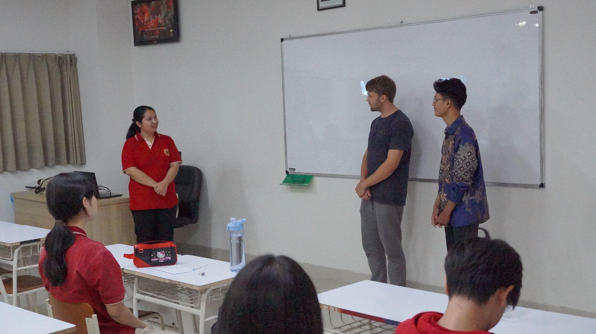 A German exchange student and a local student speak at the front of a classroom.