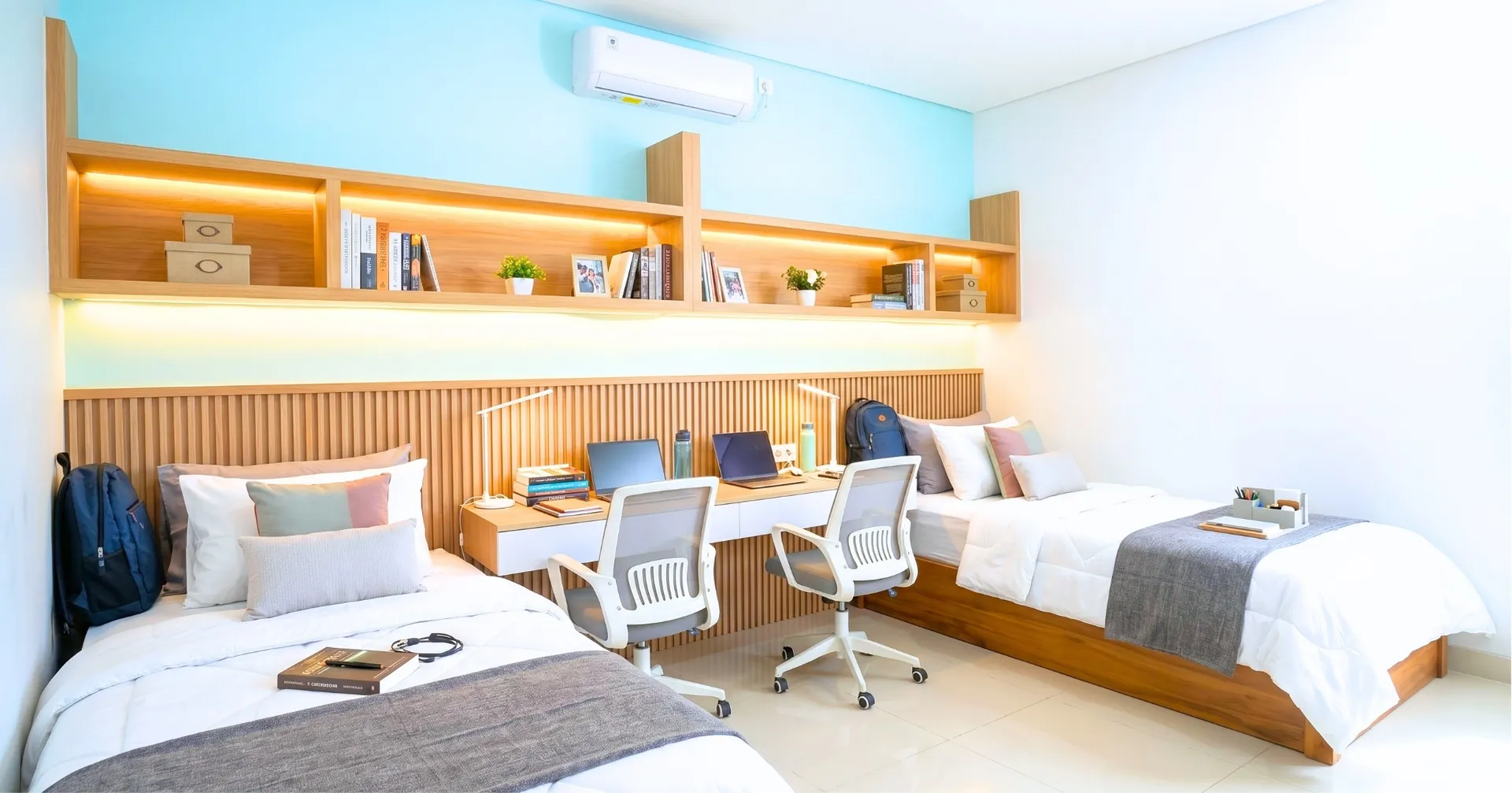 Kamar asrama mahasiswa dengan dua tempat tidur dan area belajar bersama